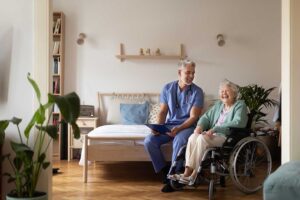 An older adult in a cozy common room, enjoying a cup of tea and chatting with other residents at a small table.