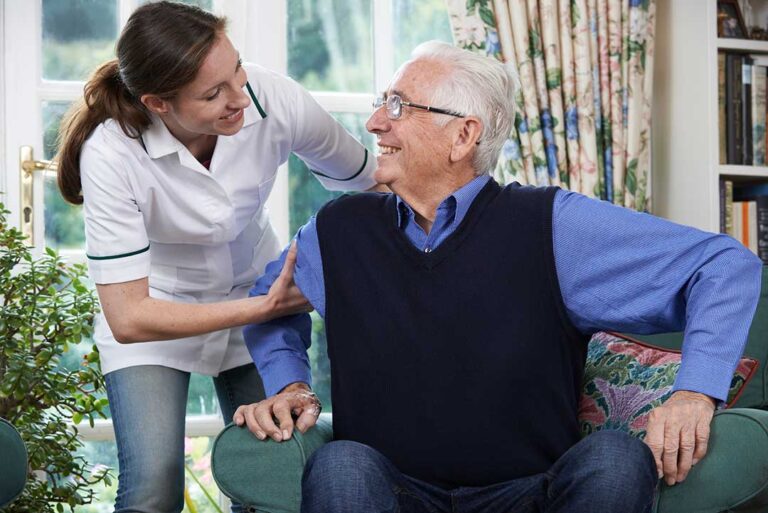 Resident and caregiver calmly discussing concerns at a table in a bright assisted living common room.